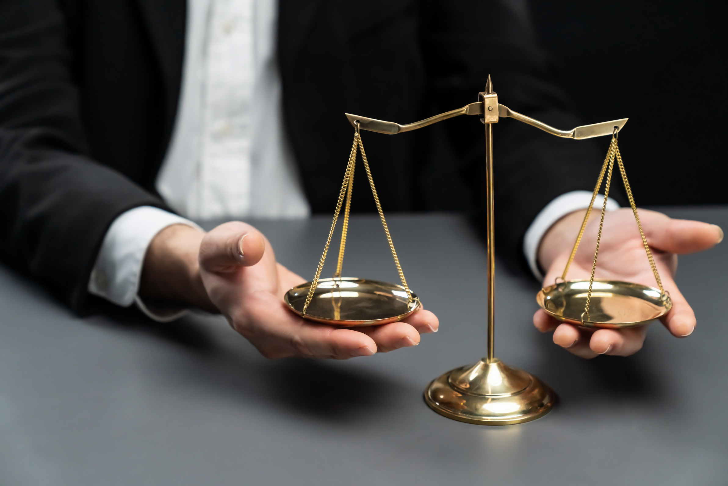 Lawyer in black suit with golden scale balance in office. equility